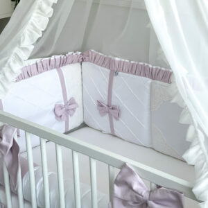 Beautiful rose and white bed bumper with vintage details protects the edges of a baby bed